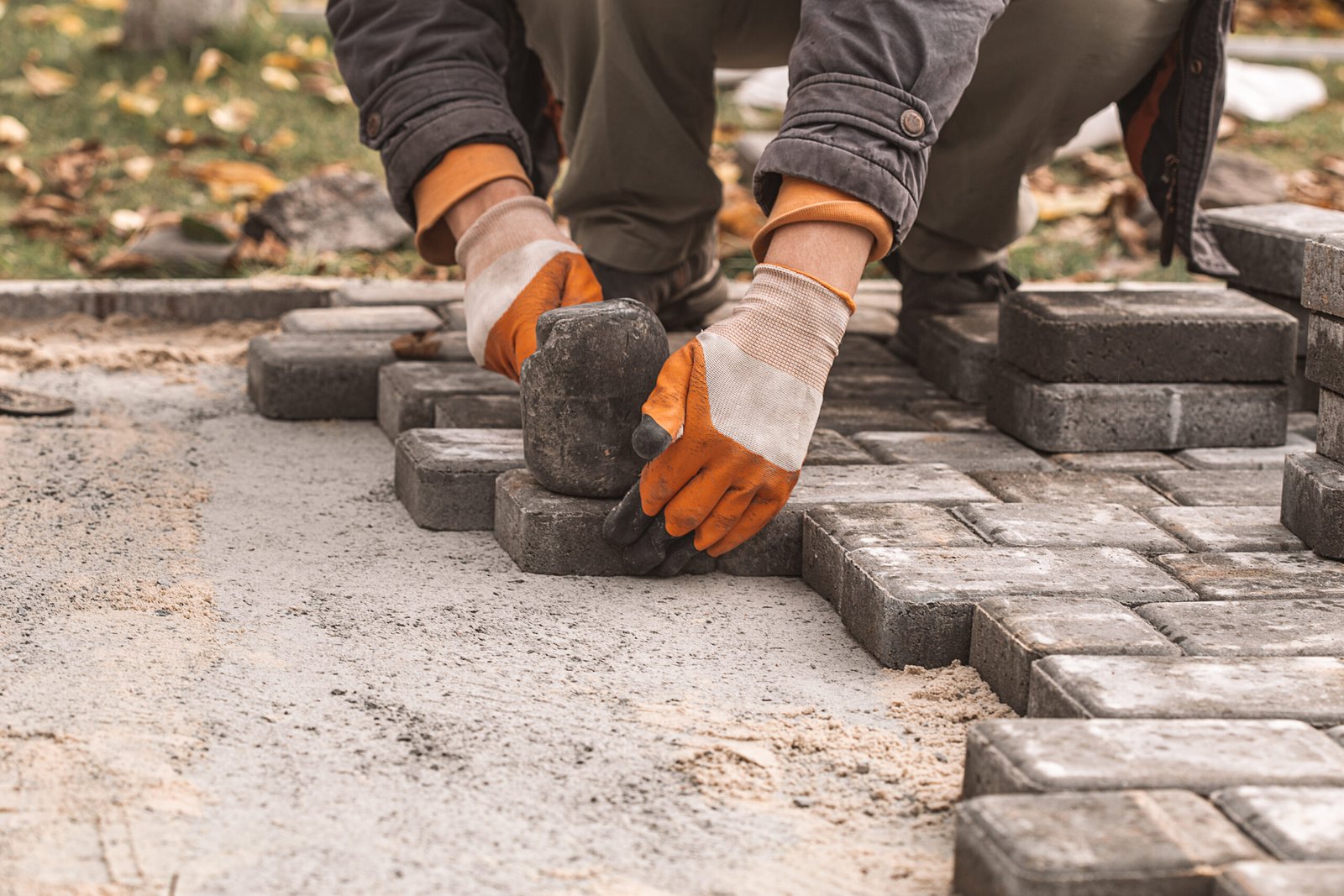 Laying paving slabs close-up. Road surface, construction. Sidewalk repair. Worker laying stone paving slab. Laying tiles in the city park garden . Manual fixed tessellated paving slabs Laying paving slabs close-up. Road surface, construction. Sidewalk repair. Worker laying stone paving slab. Laying tiles in the city park garden .